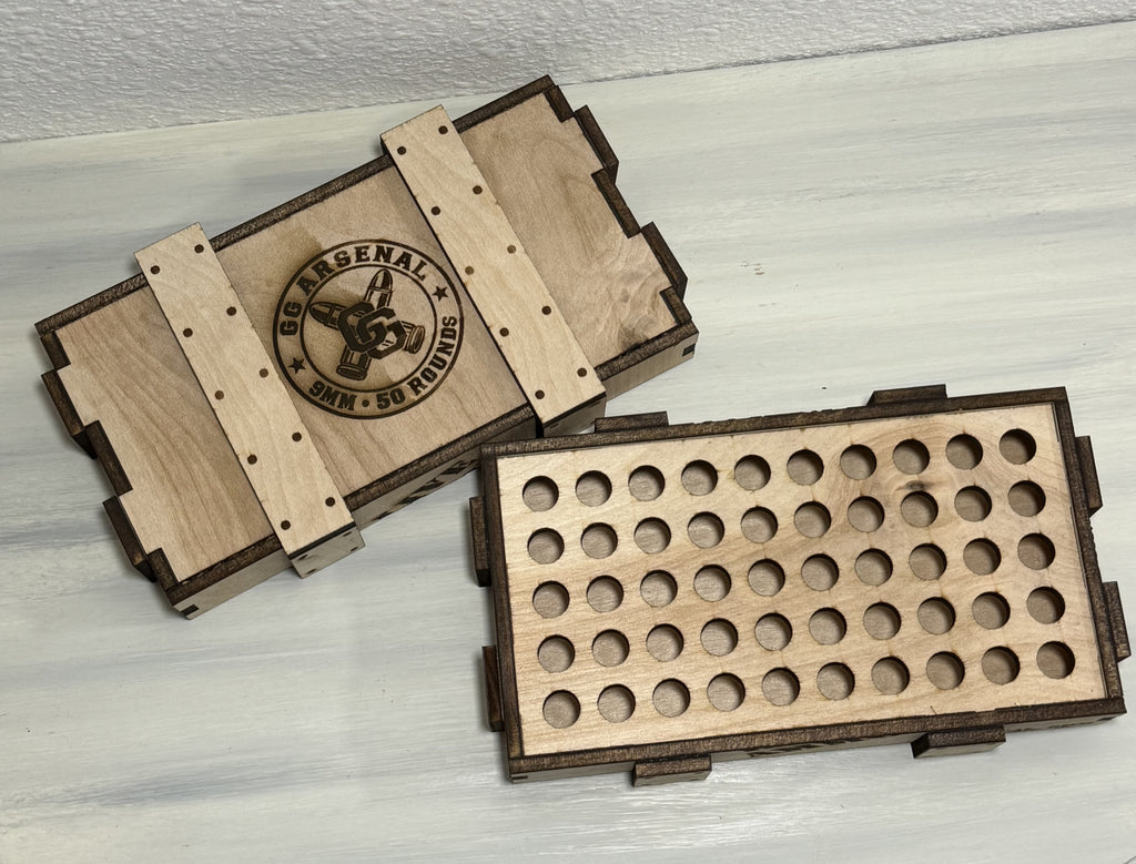 Overhead view of the empty 50-position wooden insert beside the engraved GG Arsenal lid.