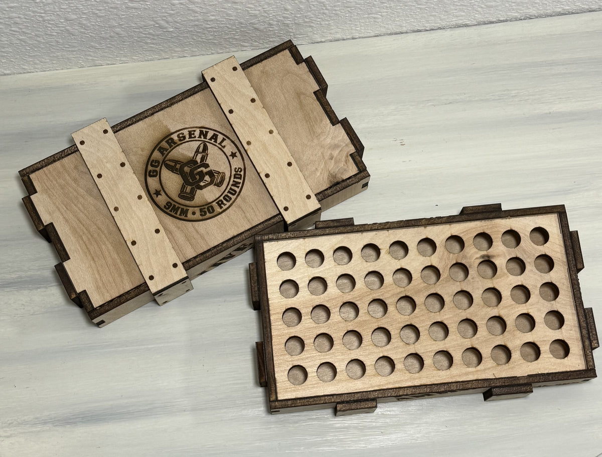 Overhead view of the empty 50-position wooden insert beside the engraved GG Arsenal lid.