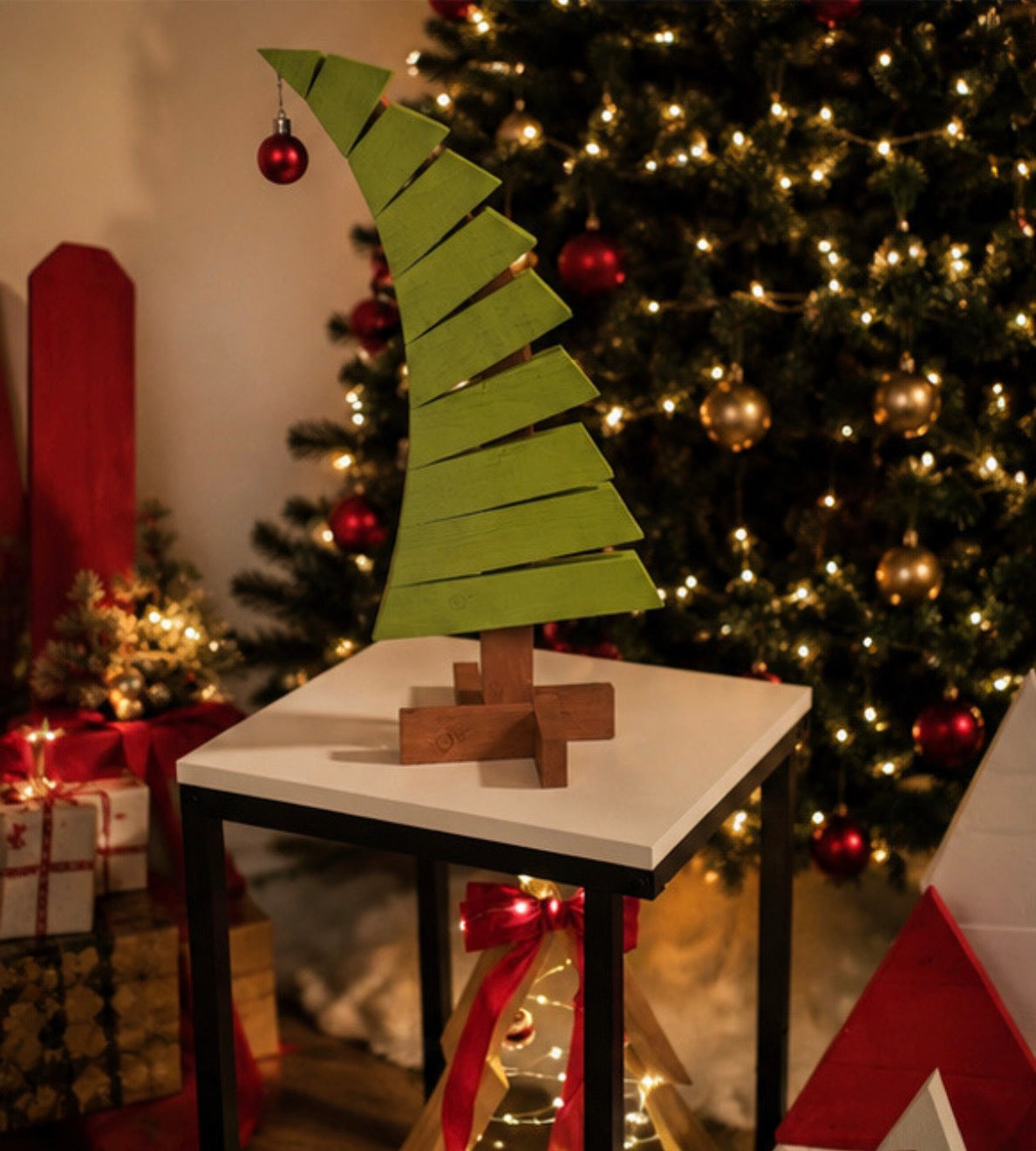 Green curved wooden Christmas tree and red ornament on a white tabletop in a holiday setting