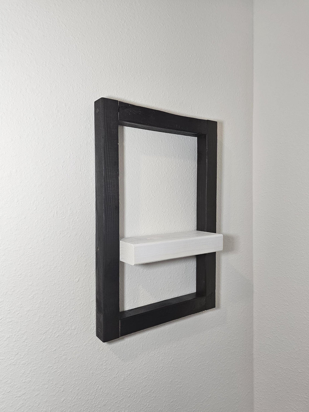 Angled view of the black and white framed wood shelf
