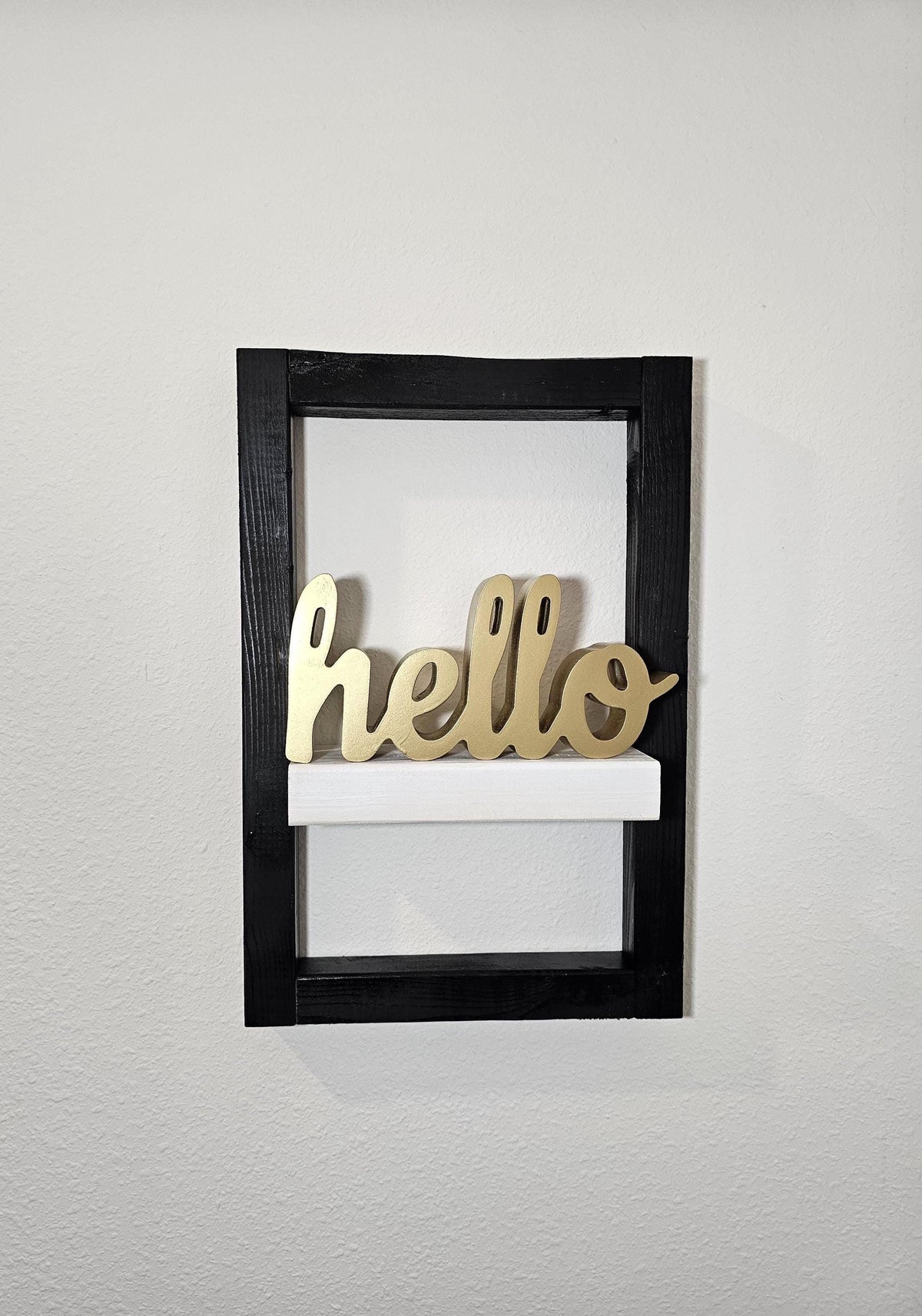 Framed wall shelf styled with a gold hello sign